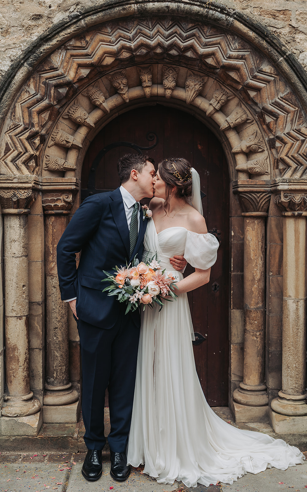 Bride and groom kissing in Norman Arch at St Ebbe's