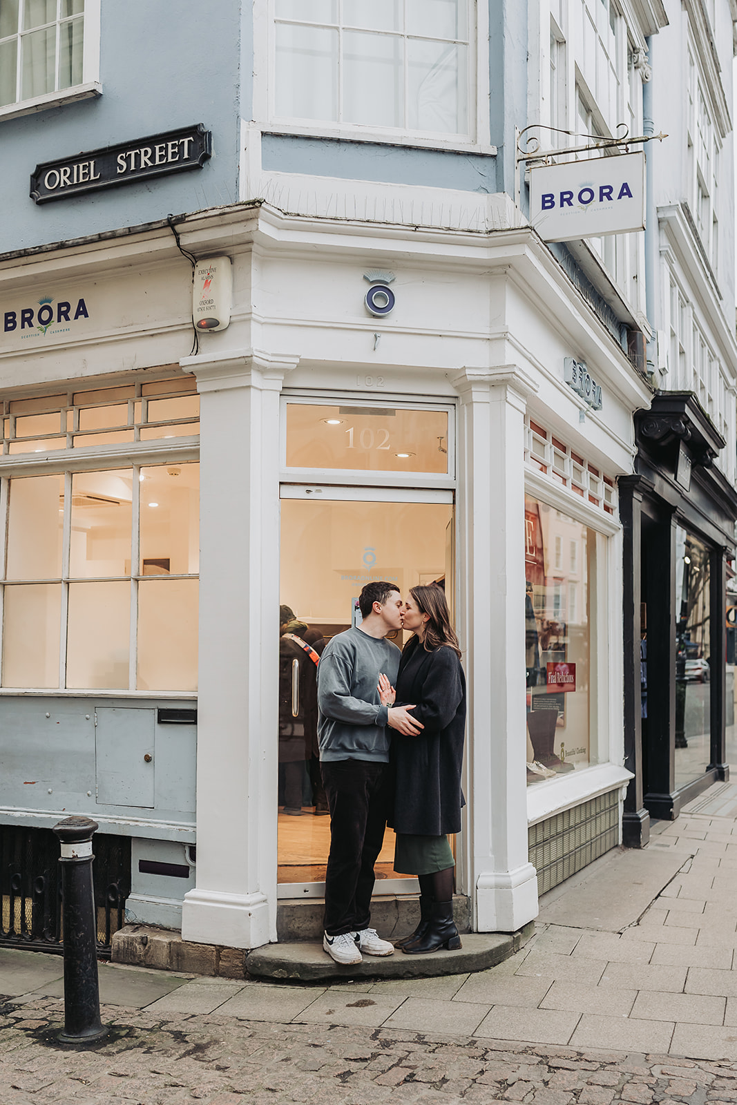 Couple kissing on step of shop in Oxford for engagement photoshoot
