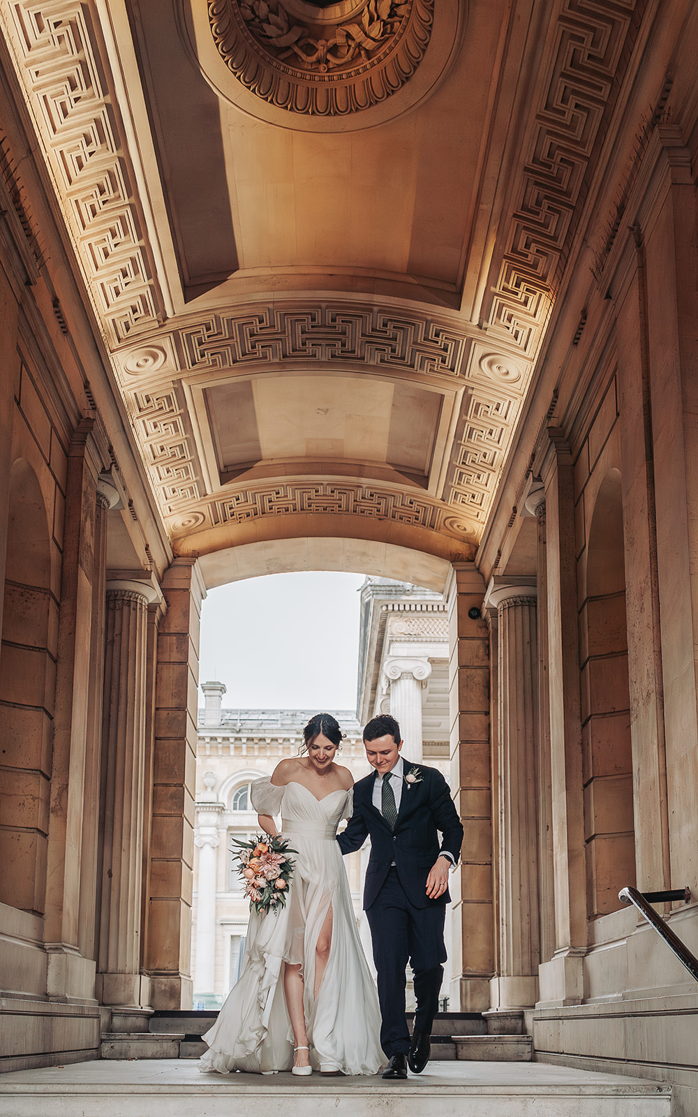 Bride and groom walking looking down at Ashmolean Museum Oxford