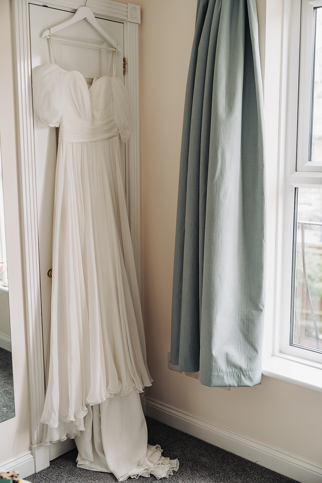 Pre-loved wedding dress hung up on door