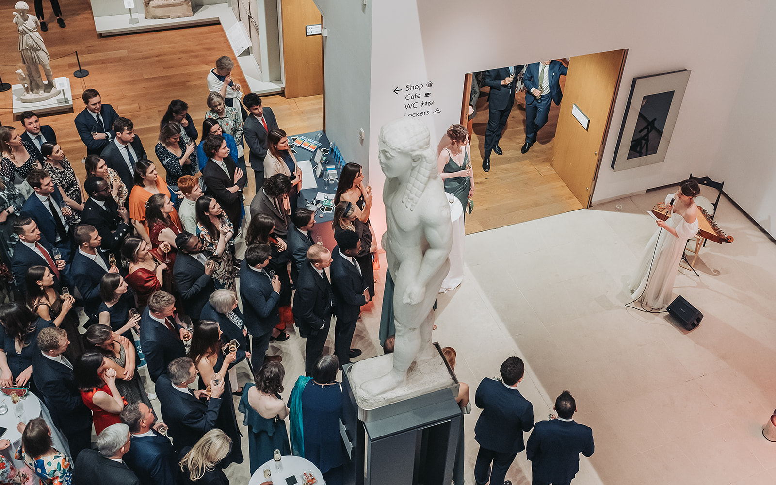 Guests watching bride give speech in atrium of Ashmolean museum
