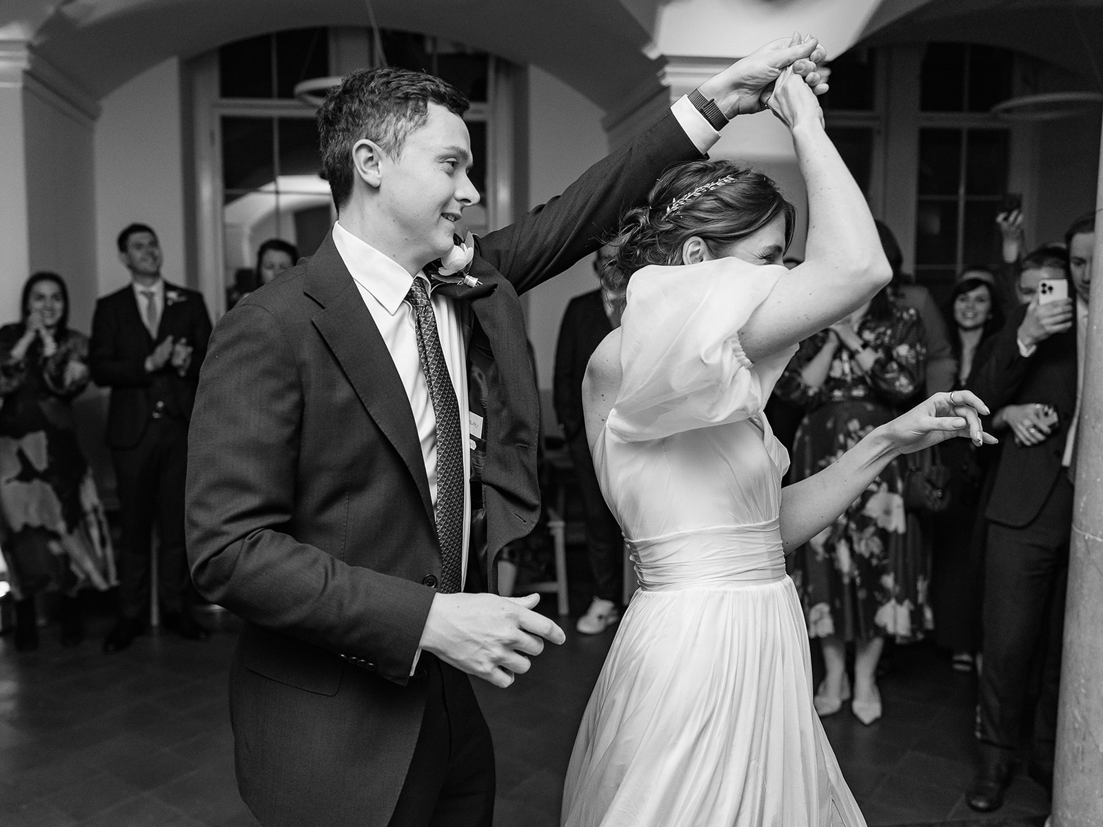 Black and white photo of groom spinning bride on dancefloor