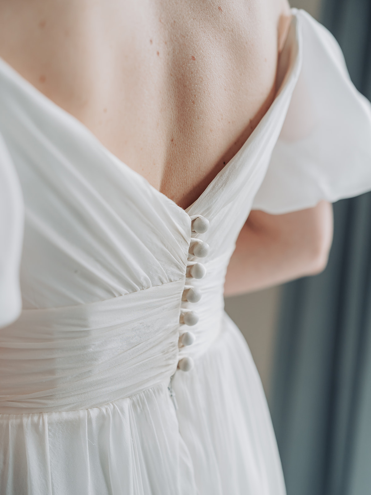 Close up of white buttons and ruche detail at back of wedding dress