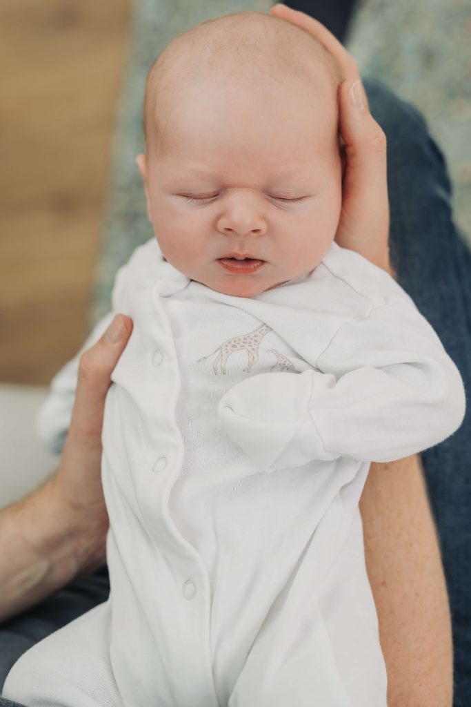 newborn baby wearing white babygrow asleep