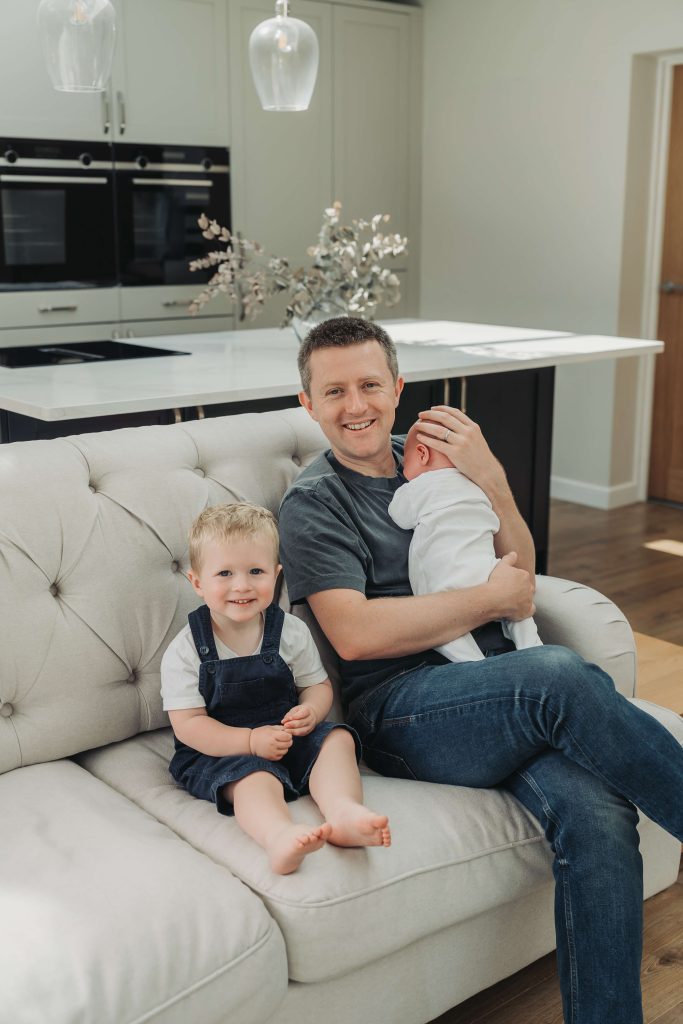 Dad, toddler boy and baby on sofa in the kitchen