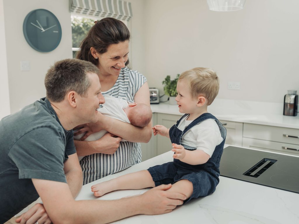 Toddler boy on worktop in the kitchen with family