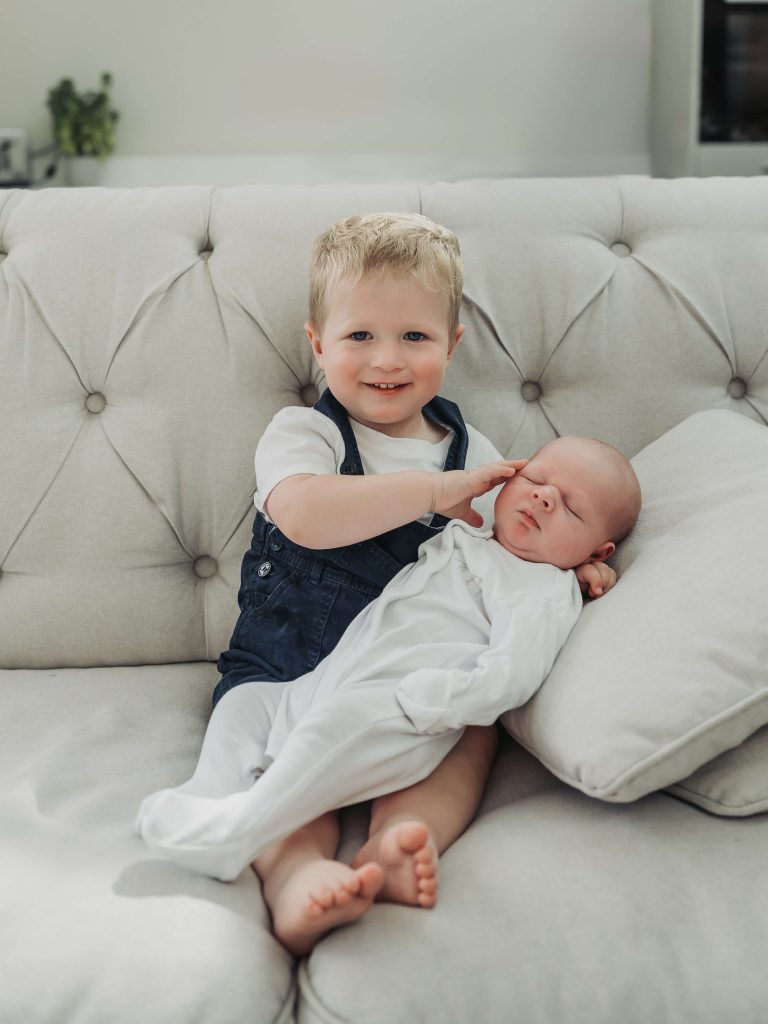 toddler bot holding baby brother and stroking him