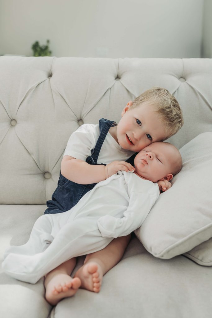 toddler boy leaning and cuddling newborn baby