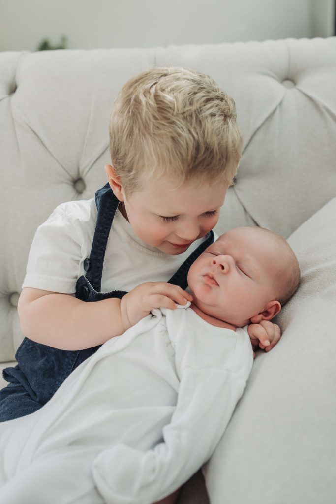 Close up of toddler boy looking at sleeping baby brother