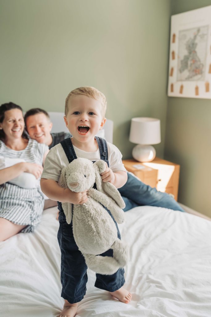 Toddler boy making cheeky face whilst holding giant fluffy bunny