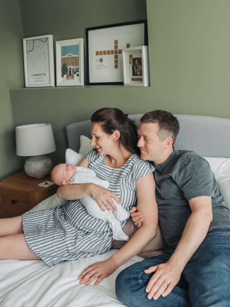 Mum, dad and baby on the bed together during a newborn photoshoot at home