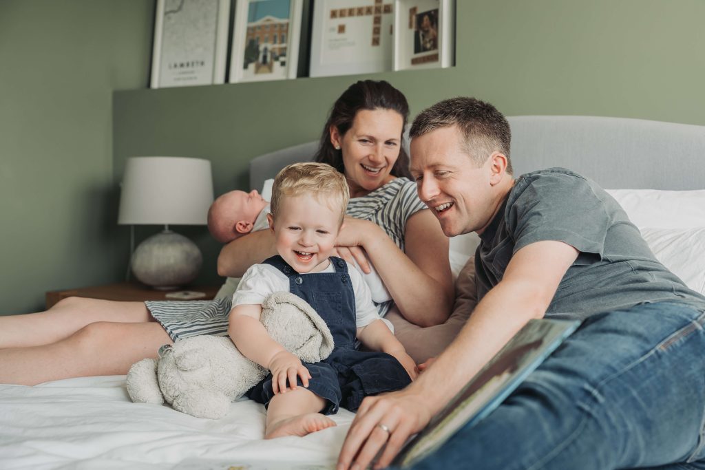 Family laughing and smiling whilst looking at a book