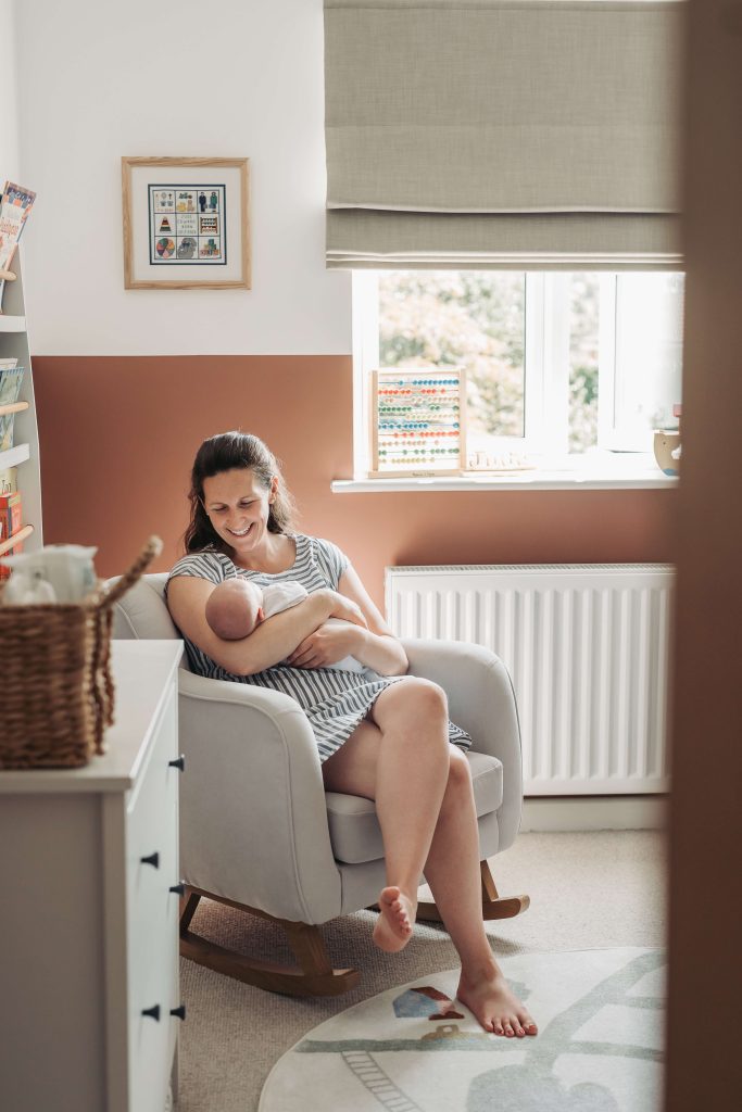 Mum sat in chair smiling down at newborn baby