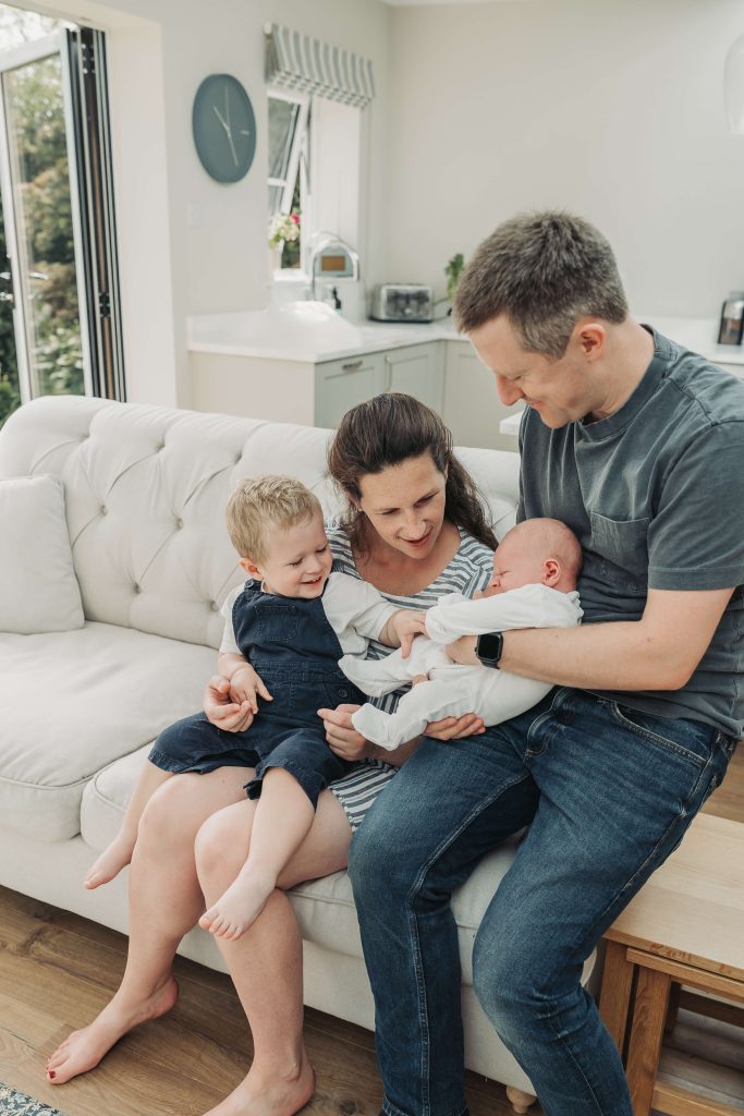 Family on the sofa interacting with newborn baby