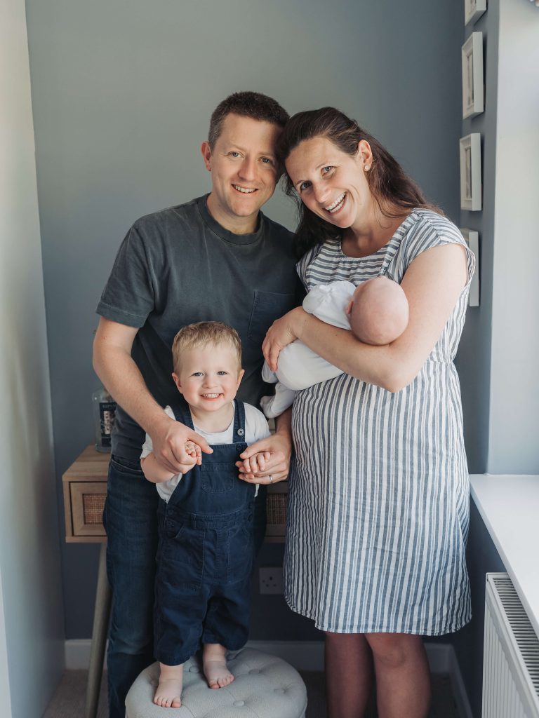 Family portrait smiling at the camera with mum, dad, toddler boy and baby