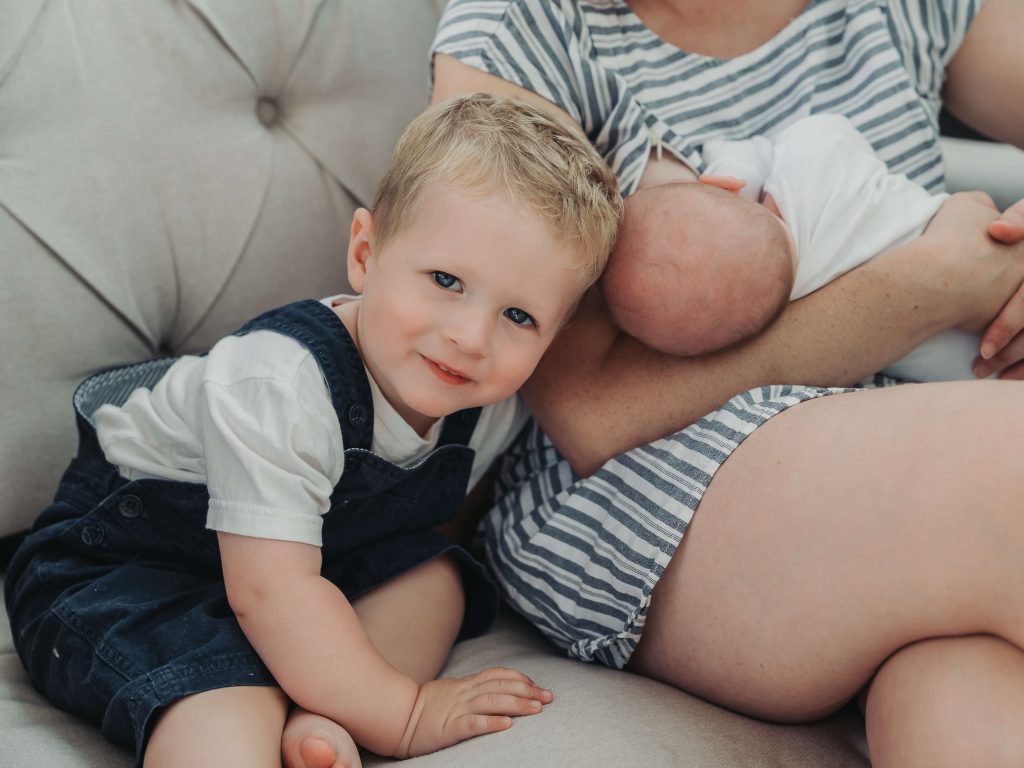 Toddler boy with head close to baby sibling