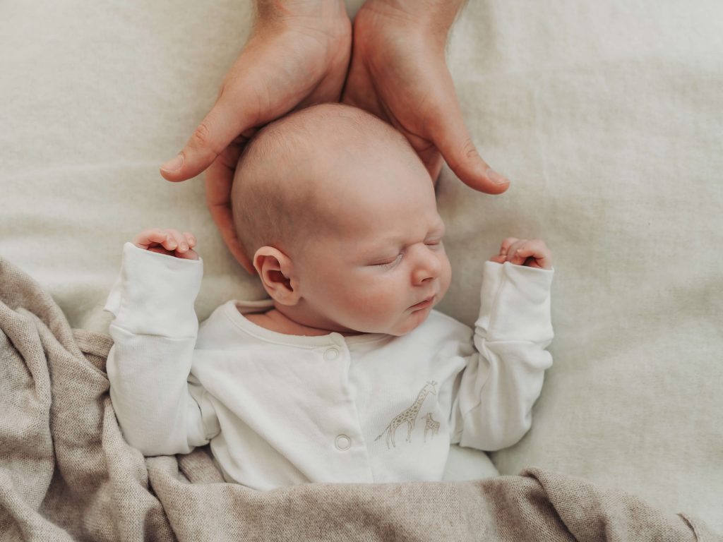 Portrait of sleeping baby with adult hands under baby's head