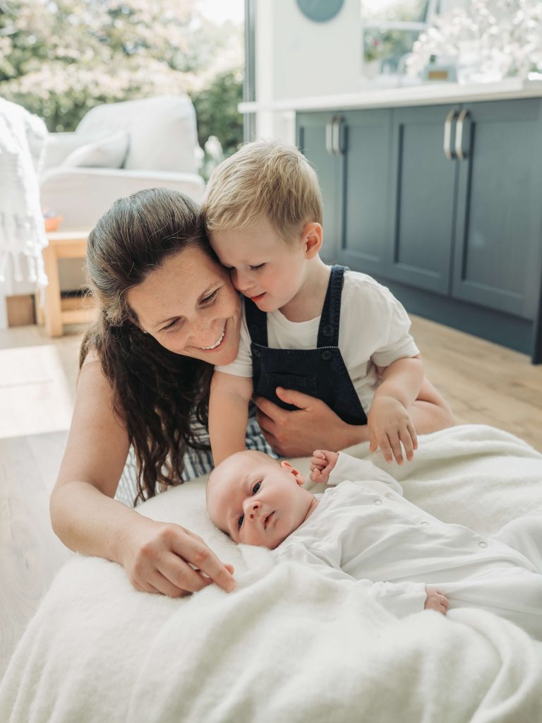 Baby on beanbag whilst mum and brother look on during a newborn photoshoot at home