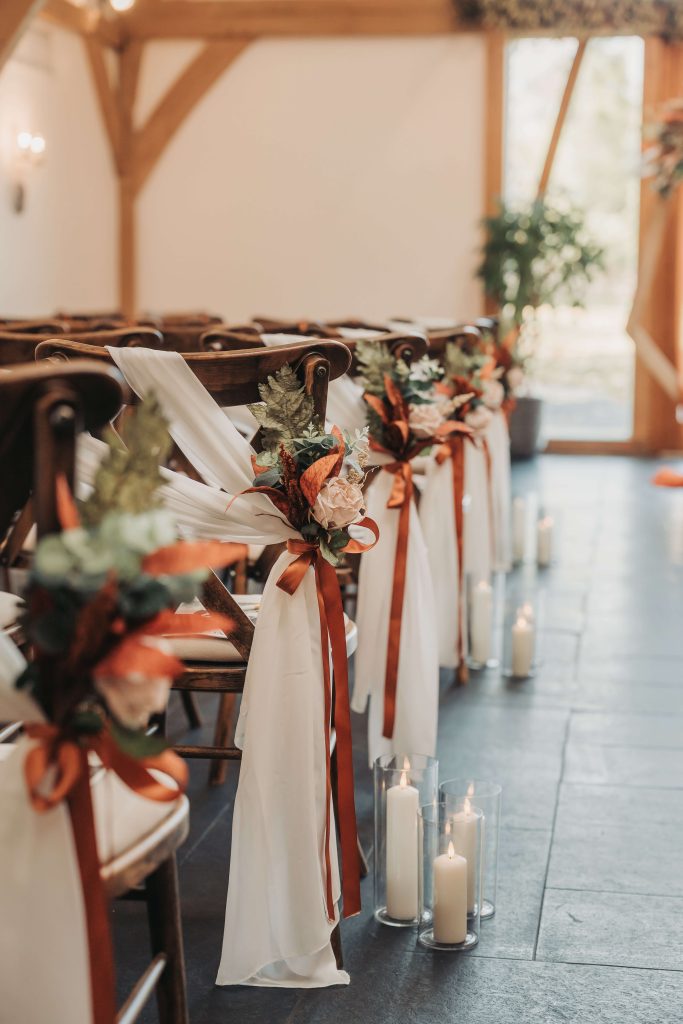 orange ribbons and flowers on ceremony chairs at Mythe Barn wedding venue