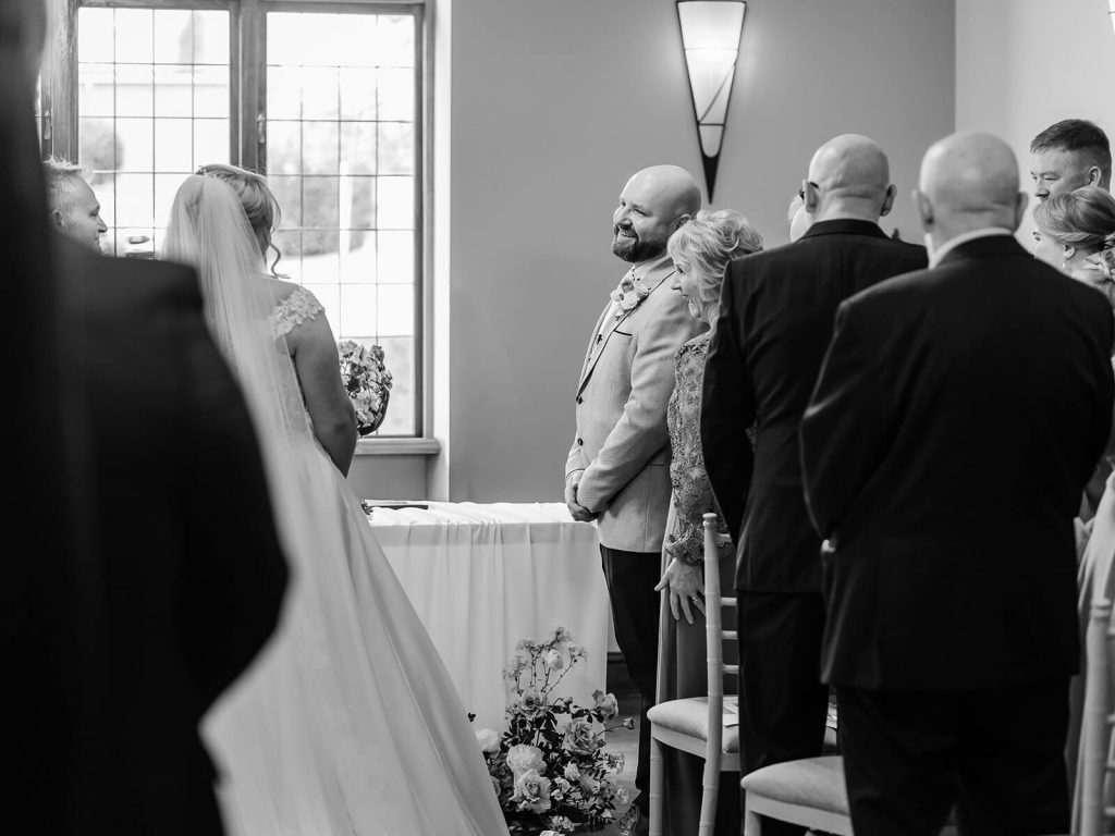 Black and white image of groom reaction during wedding ceremony