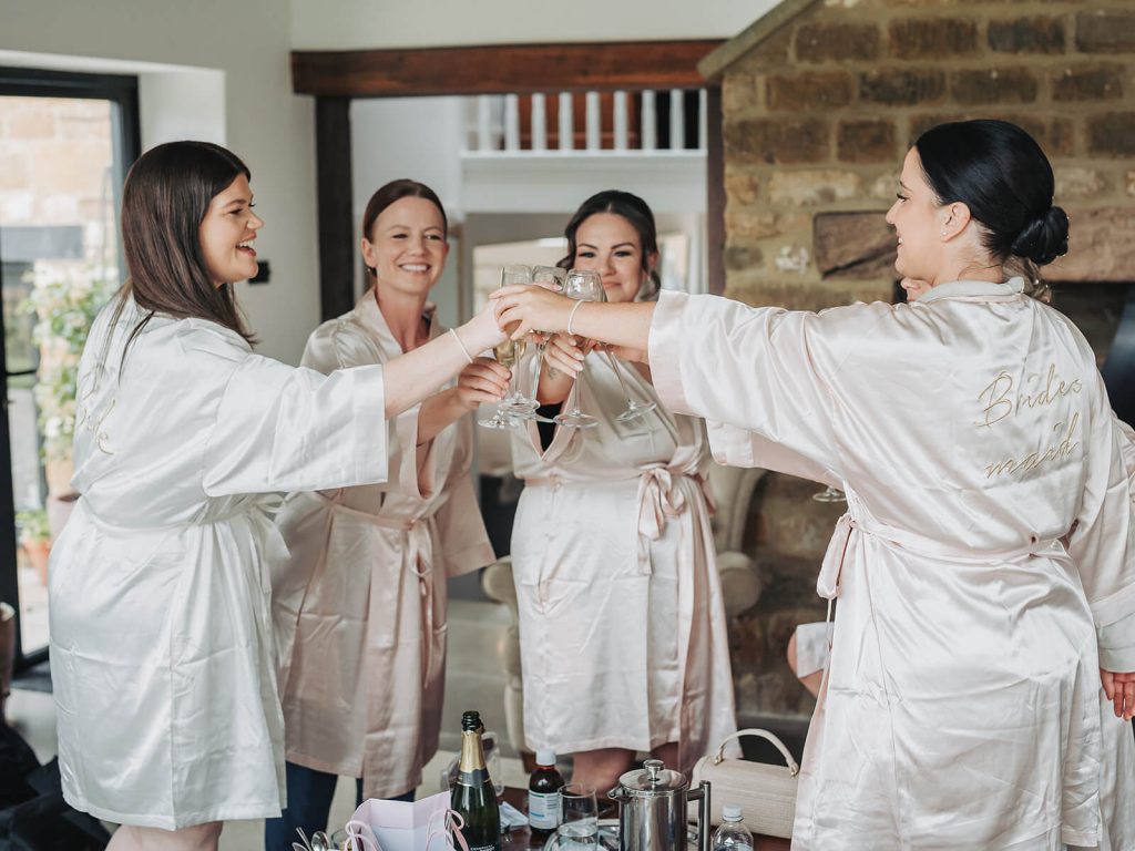 Bridal party in dressing gowns clinking champagne glasses