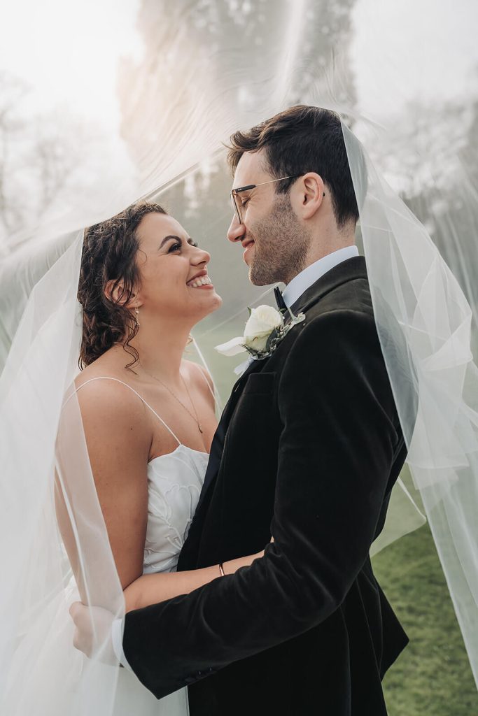 bride and groom smiling under veil