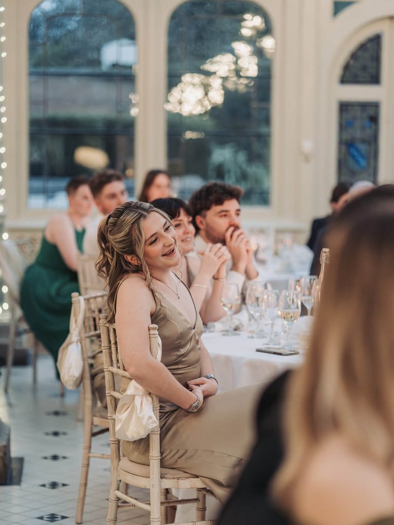 bridesmaid in champagne coloured dress smiling during speeches