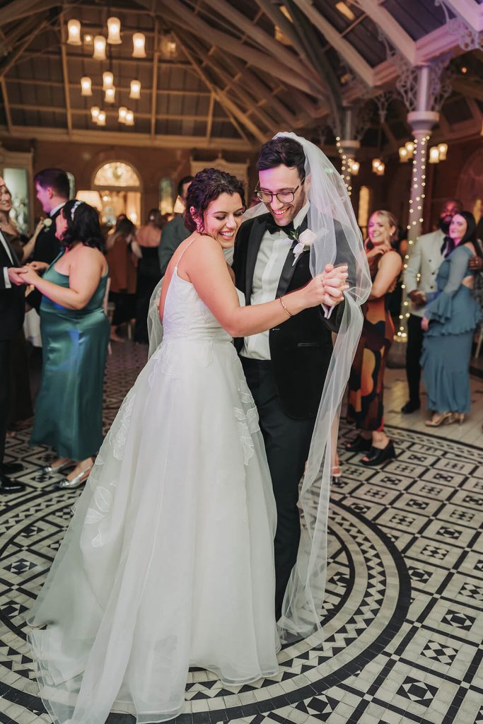 groom with wedding veil on head dancing with bride