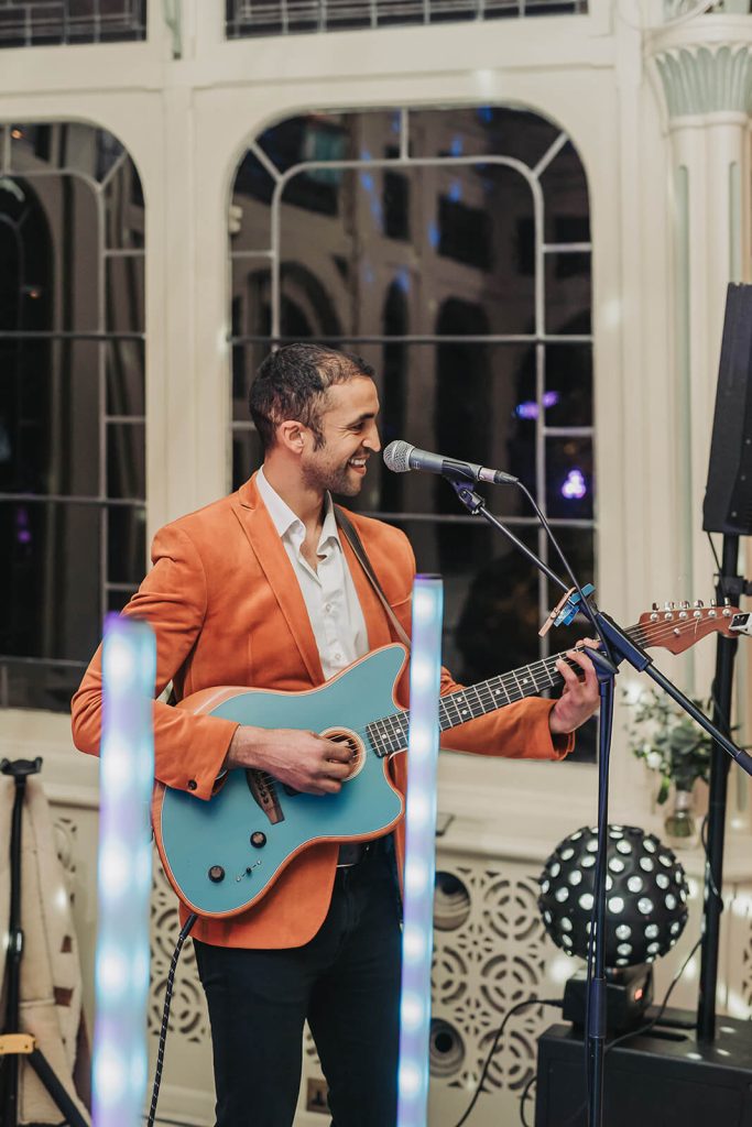 man in orange blazer playing guitar