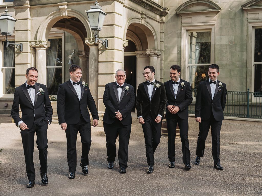groom and groomsmen in tuxedos walking outside of Kilworth House