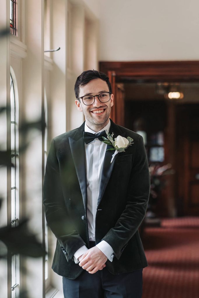groom portrait of groom laughing in the distance in green velvet tuxedo