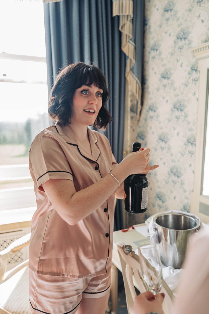 bridesmaid opening bottle of champagne
