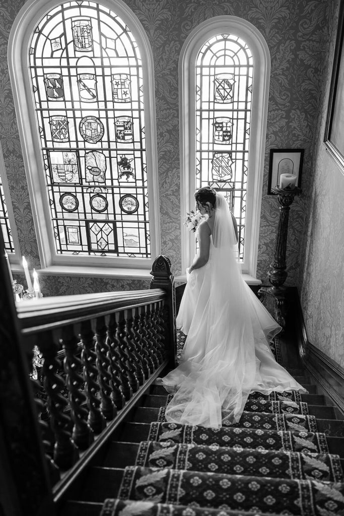 black and white photo bride walking down the stairs at Kilworth House