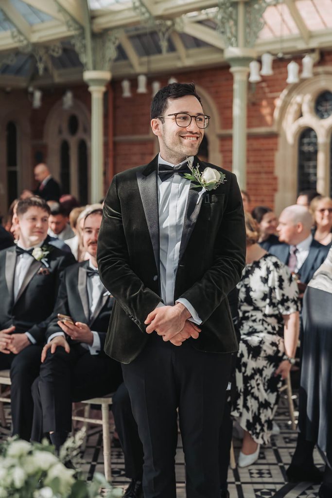 groom smiling waiting at top of the aisle