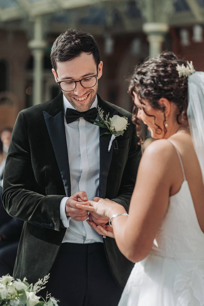 groom putting ring on bride's fingers
