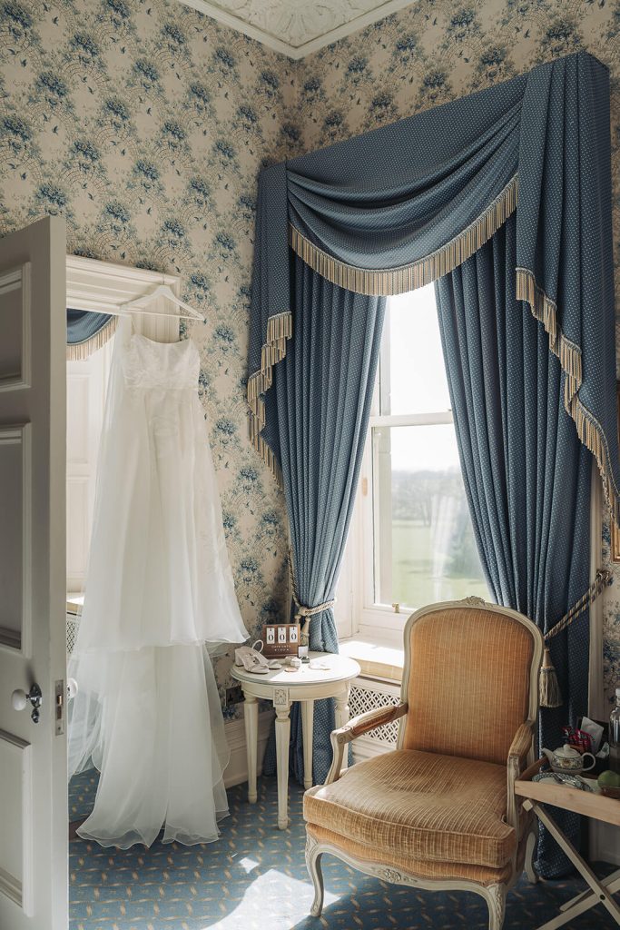 Wedding dress hung up in Victorian hotel room at Kilworth House