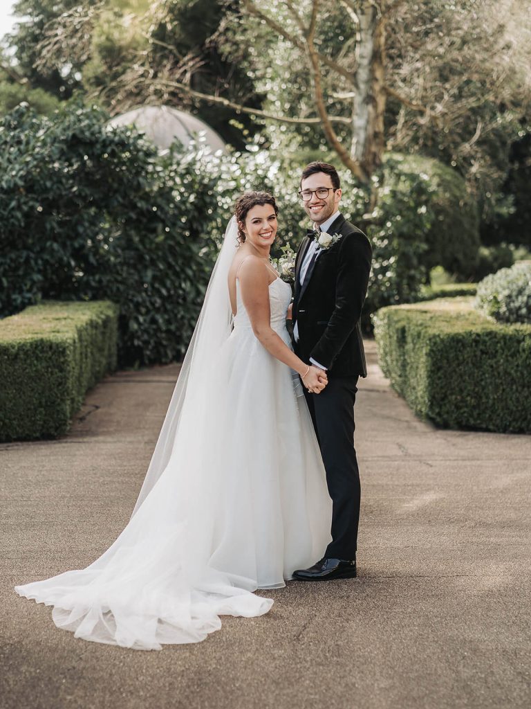 wedding couple holding hands and smiling at the camera