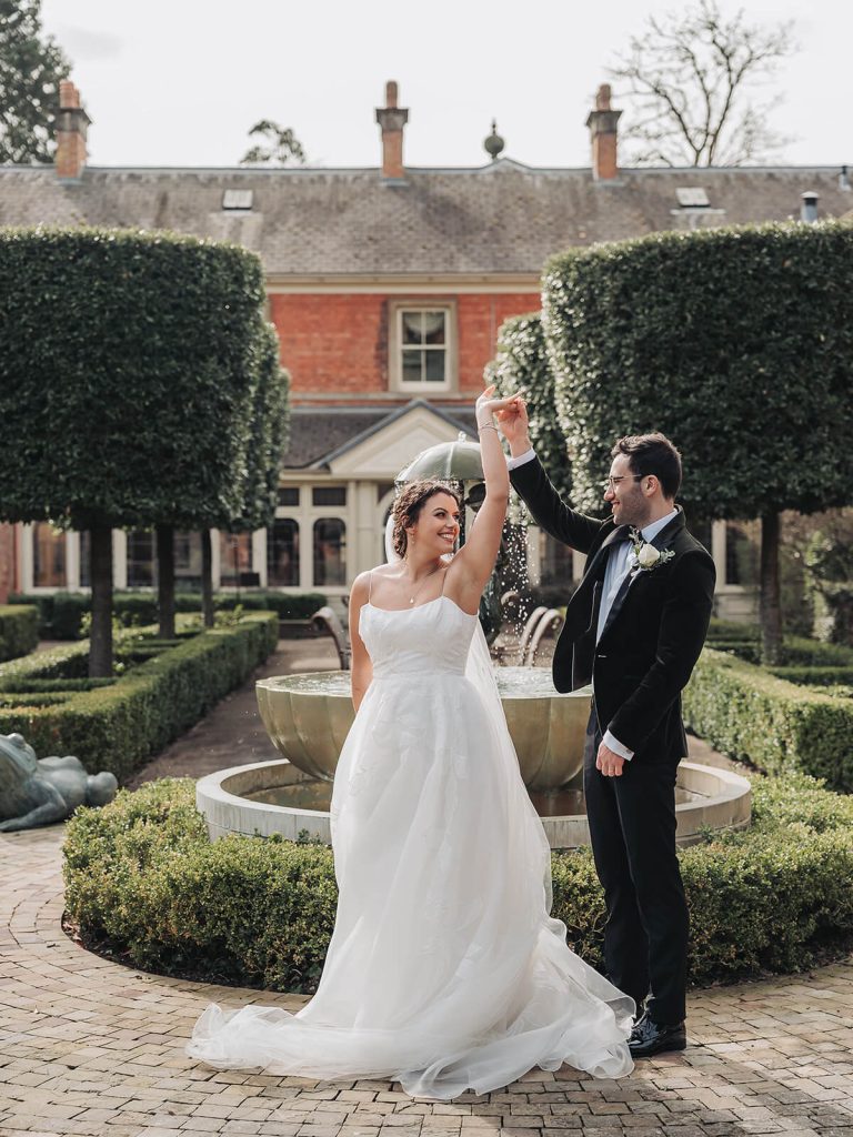 groom twirls bride in garden at Kilworth House