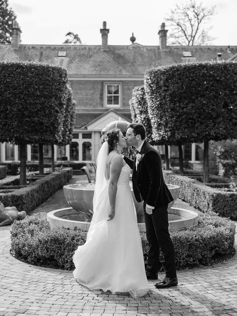 black and white photo of wedding couple kissing in garden at Kilworth House