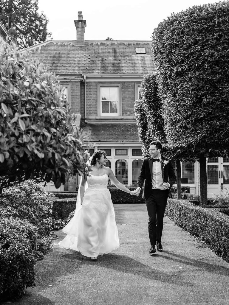 black and white photo of couple running holding hands and running