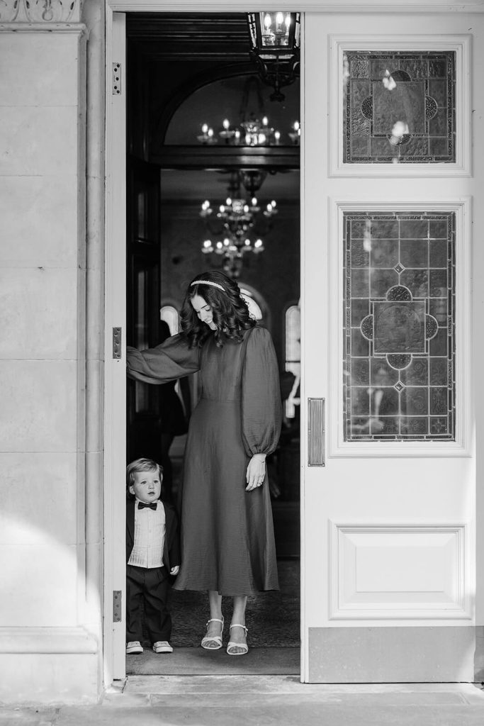 black and white photo of little boy in tuxedo at doorway