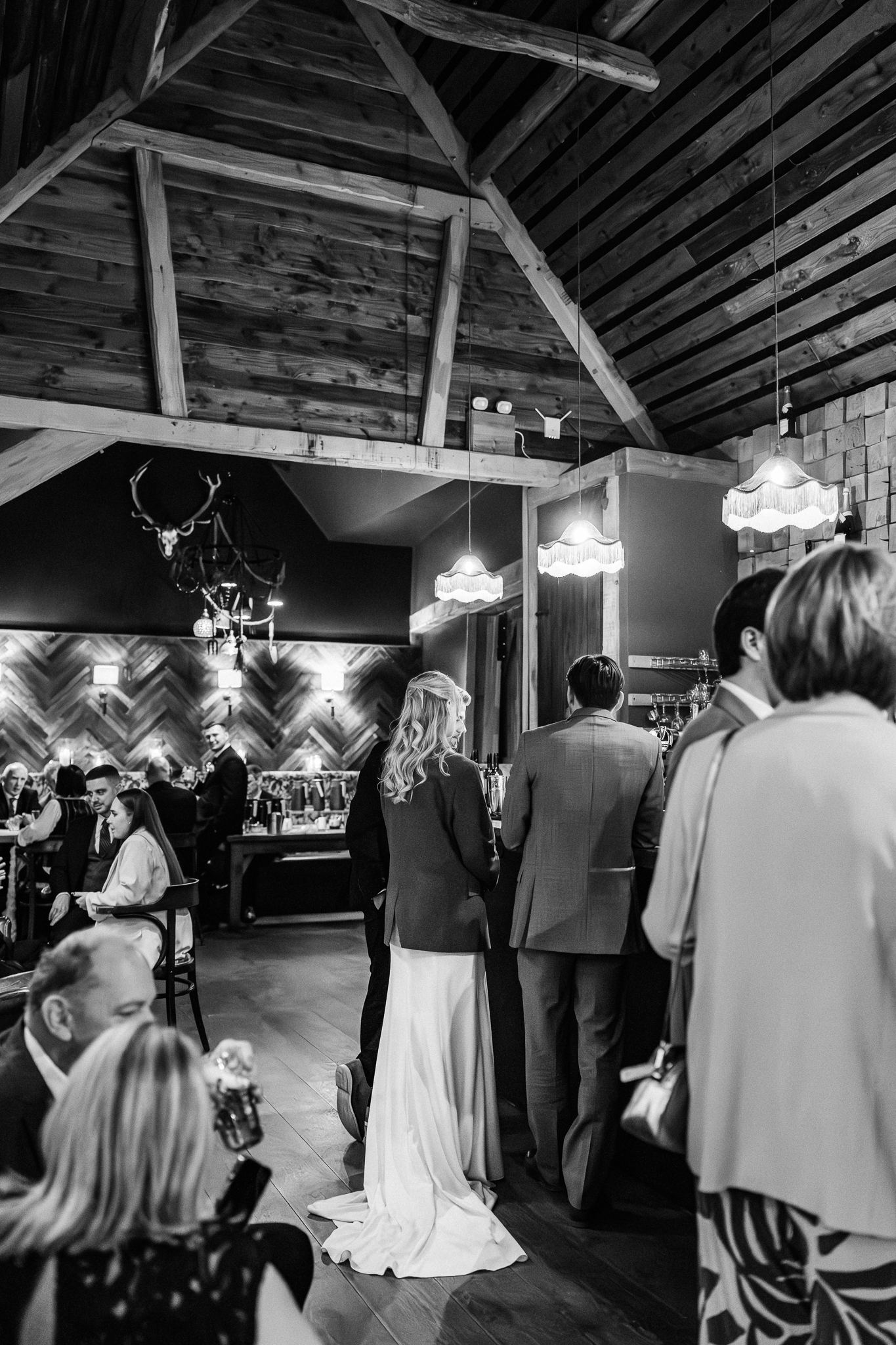 black and white photo of bride at bar wearing suit jacket