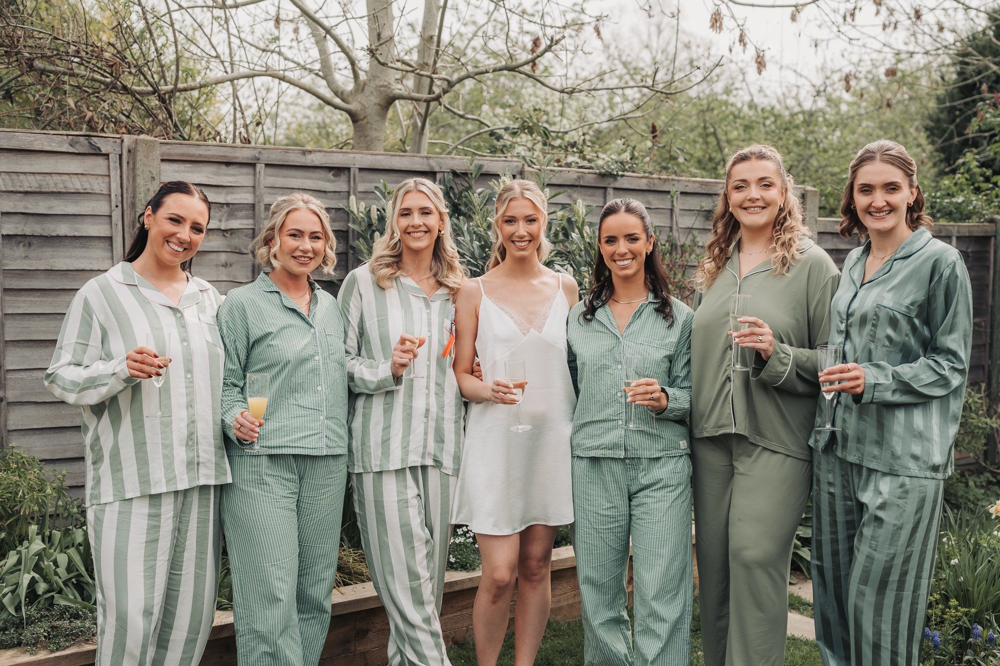 bridal party in pyjamas in garden smiling at camera