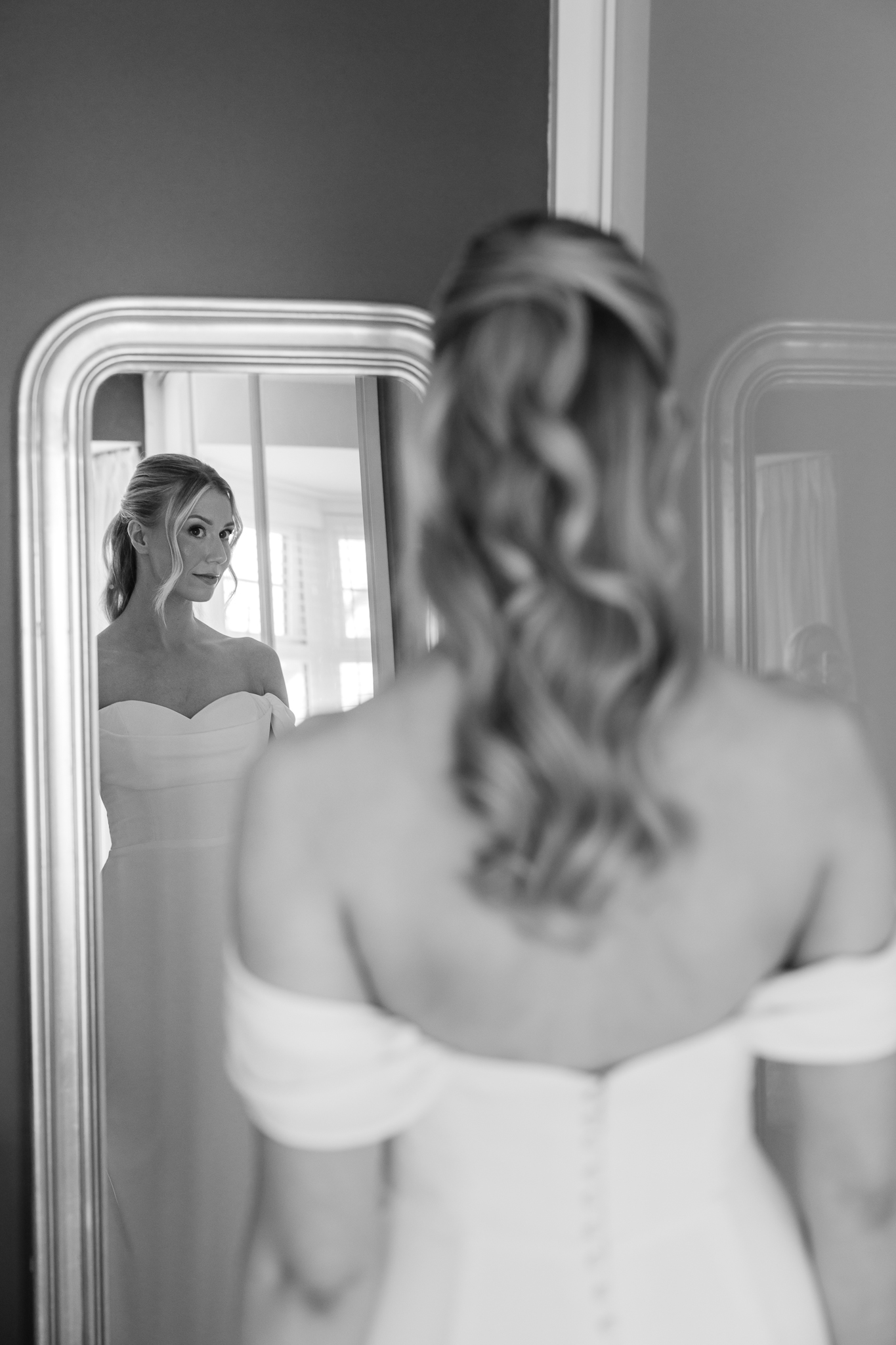 black and white photo of bride looking in the mirror