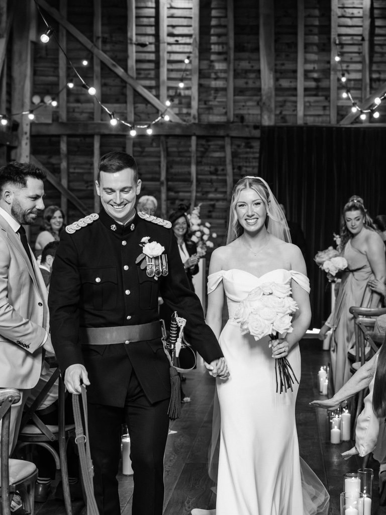 black and white photo of bride and groom walking down the aisle