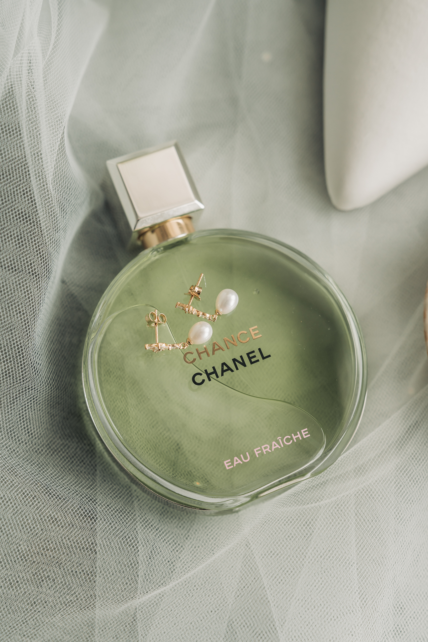 green perfume bottle with pearl earring on top at bridal prep in Hitchin