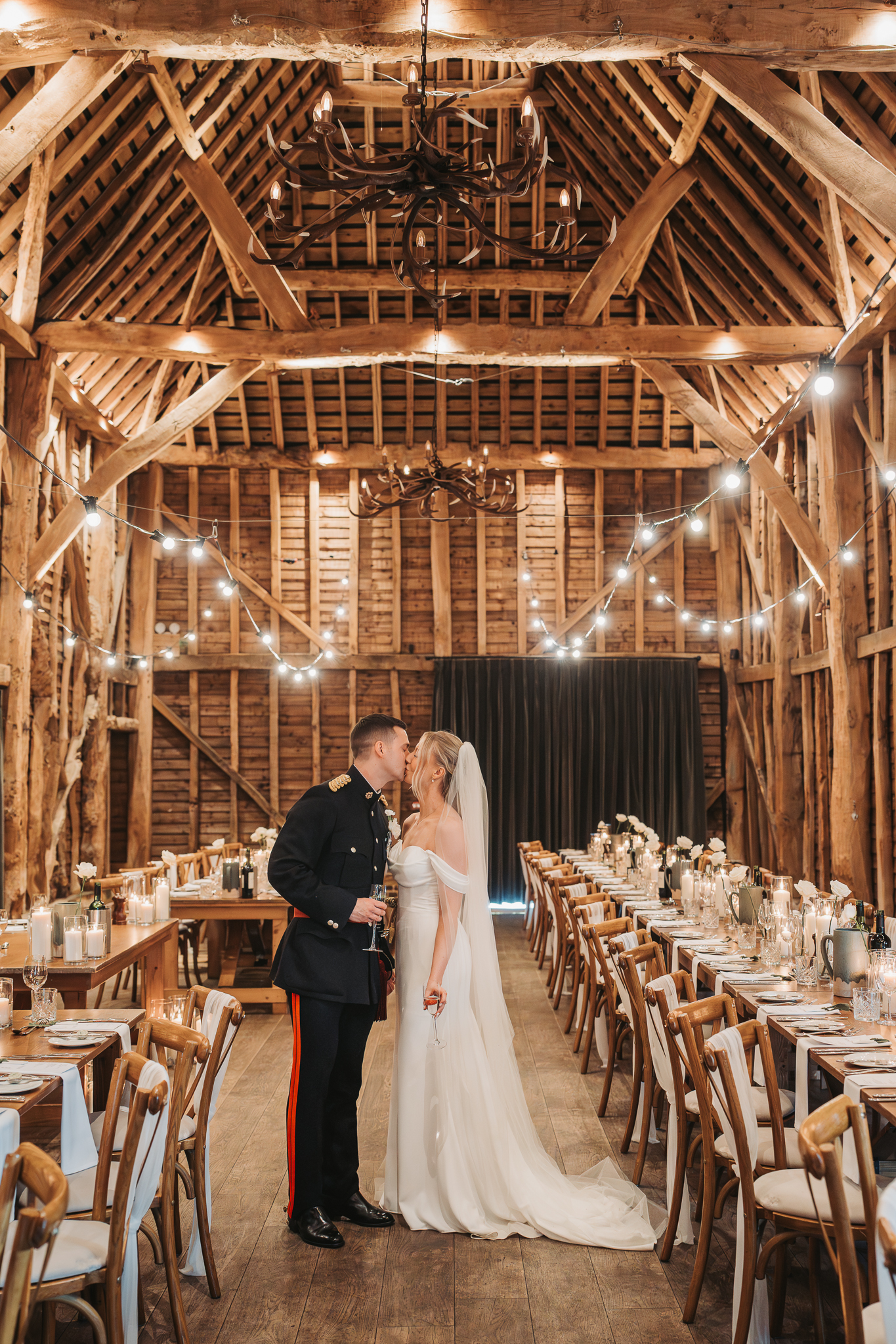 bride and groom kissing under festoon light at barn at Redcoats Hitchin