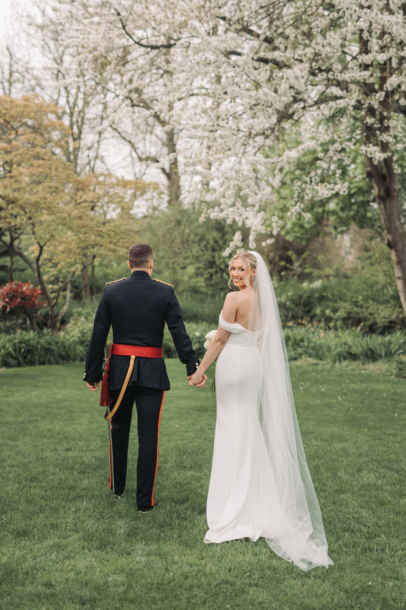 bride looking over her shoulder holding hands with groom