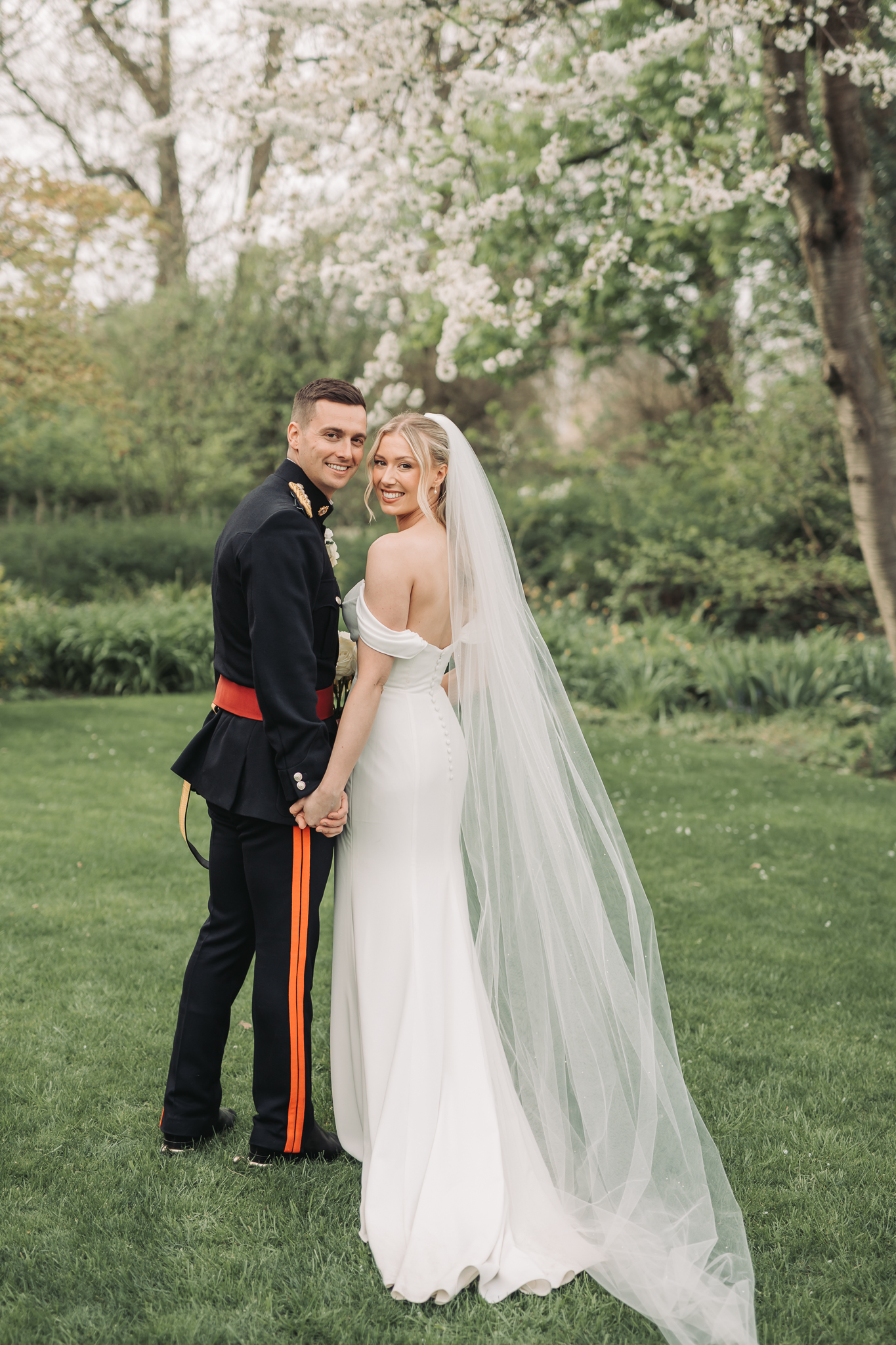 bride and groom both looking over shoulder and smiling at camera