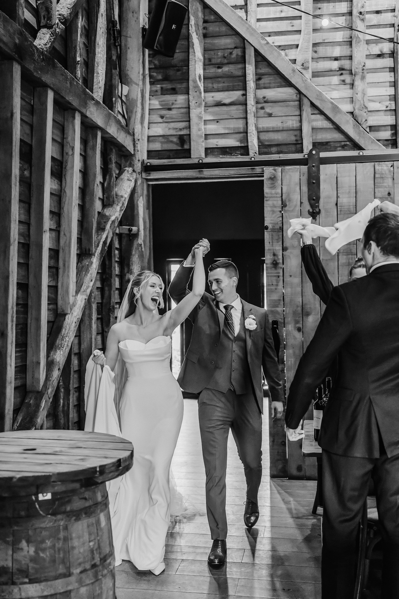 bride and groom enter barn celebrating hand in hand